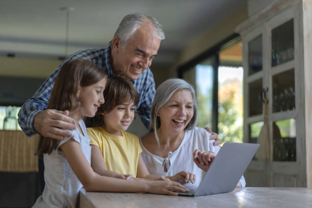 szczęśliwi dziadkowie i wnuki za pomocą laptopa na rozmowę wideo - grandparent using computer laptop dining table zdjęcia i obrazy z banku zdjęć