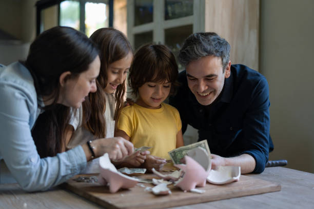 Family with two children opening the piggy bank counting coins and bills all smiling Family with two children opening the piggy bank counting coins and bills all smiling very happy lifestyles teaching little girls child stock pictures, royalty-free photos & images