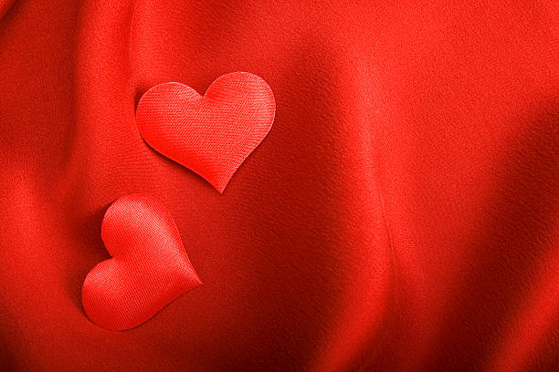 istock Two satin hearts on red silk background. 119832333