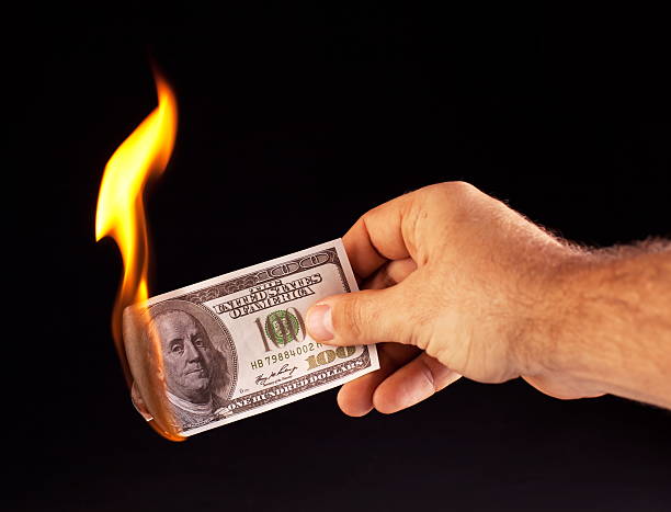 istock burning dollar in hand  on a black background. 119832391