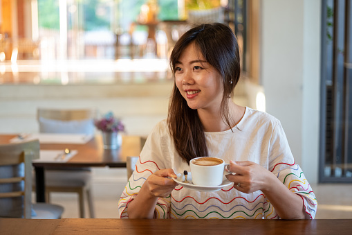 Young asian female having a coffee break in cafe