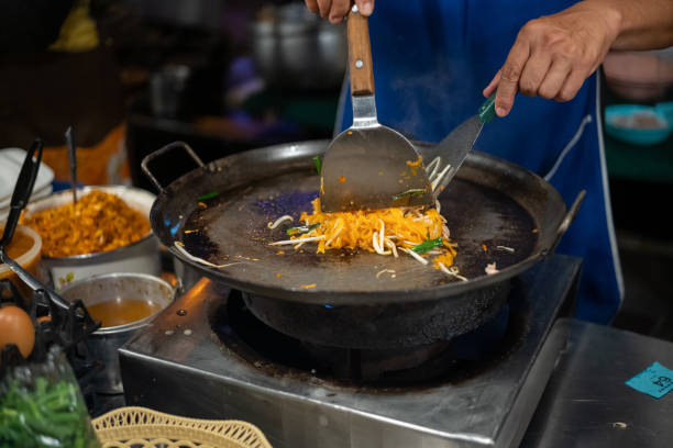 venditore di cibo di strada tailandese che prepara thai street food pad thai alla bancarella del mercato - thailand thai culture thai cuisine pad thai foto e immagini stock