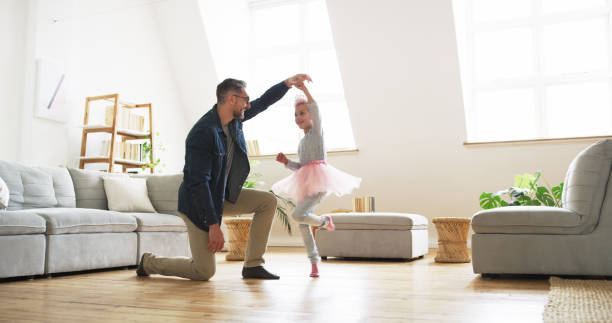 Dad will do anything to bring bliss to her days Shot of a father dancing with his little daughter at home dancing dad stock pictures, royalty-free photos & images
