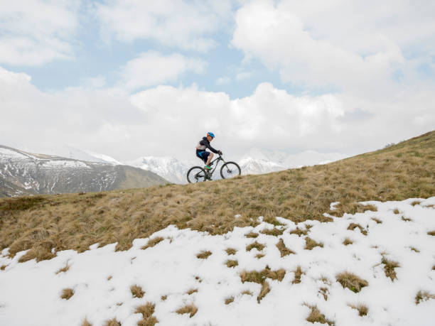 istock Mountain biker rides along snowy ridge 1198329340