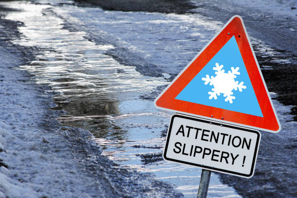 An icy road in winter with a sign Attention slippery! An icy road in winter with a sign Attention slippery! hazard sign photos stock pictures, royalty-free photos & images