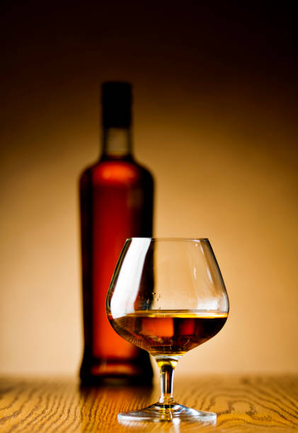 A glass of cognac lies on its side on a white background. The view from the top.