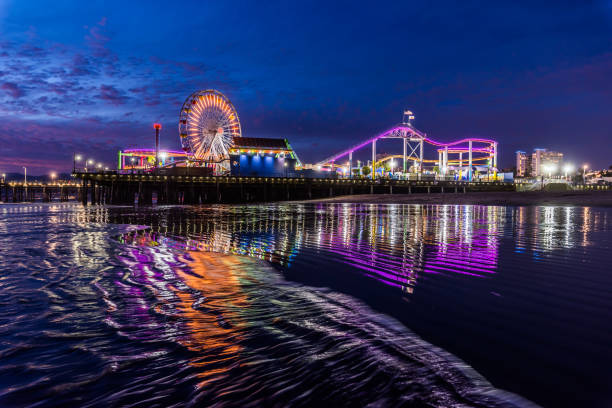 Santa Monica Pier at sundown with lights reflected in the Pacific Ocean surf