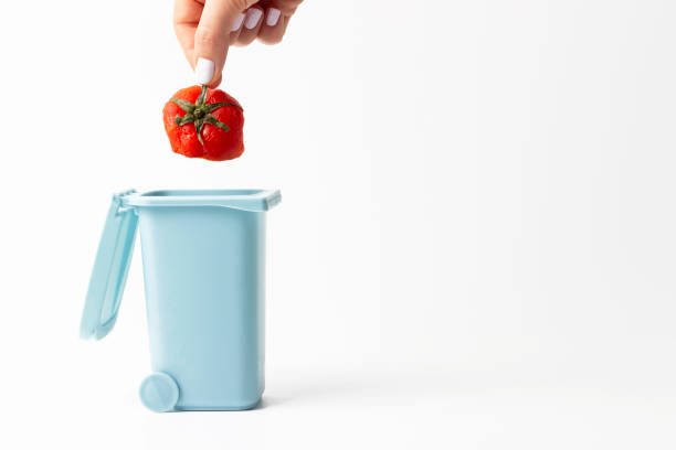 istock Female hand throws food trash into trash can on white background, copy space. 1198334270