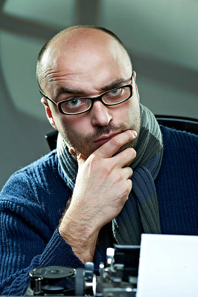 Old fashioned bald writer in glasses writing book stock photo