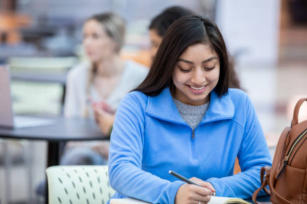 istock Female adult student taking notes while sitting at desk in student building 1198346497