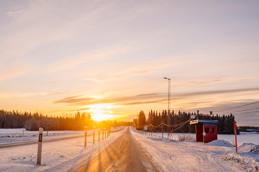 winter road in Norrland Sweden Sunrise in the morning, bus stop in rural area\nPhoto taken from car window for travelers perspective