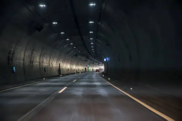 Photo of Driving though a large tunnel of a motorway with a view towards the exit