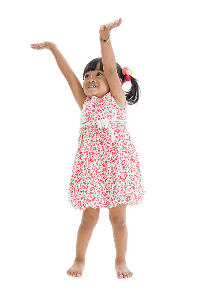 The Small girl in white gown spins, jumps, playing, smiling,  pose on white background.
