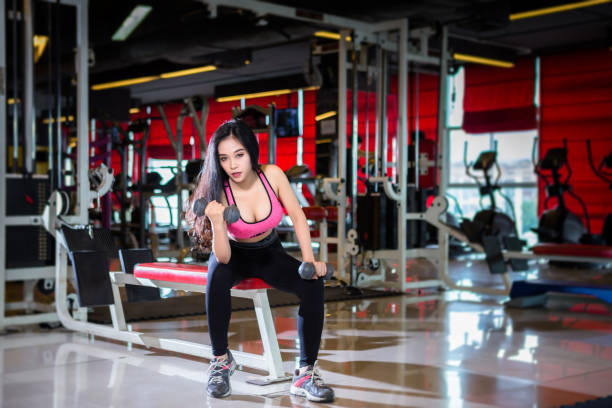 fitness azjatyckie kobiety wykonujące ćwiczenia szkolenia z hantle sport w sport siłowni wnętrza i fitness klub fitness ze sprzętem do ćwiczeń sportowych gym tle. - exercising sports training sport gym zdjęcia i obrazy z banku zdjęć