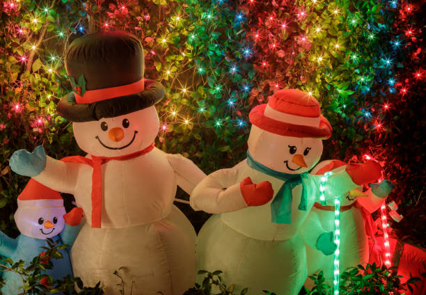 snowman familie schmückt vorgarten in der nacht - blow up doll stock-fotos und bilder