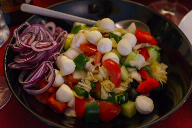istock Fresh vegetable salad with mozzarella balls decorated with red onion rings. 1198367151