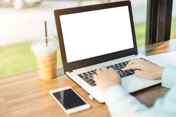 istock Close-up of business female working with laptop with blank white screen make a note document and smartphone in coffee shop like the background. 1198368647
