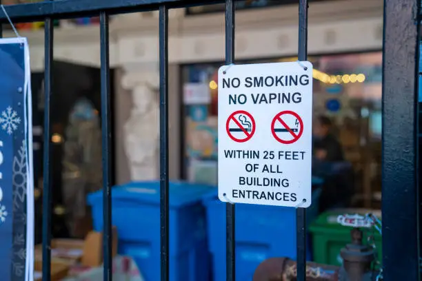 Photo of No smoking no vaping logos and crossed out on gate in front of building