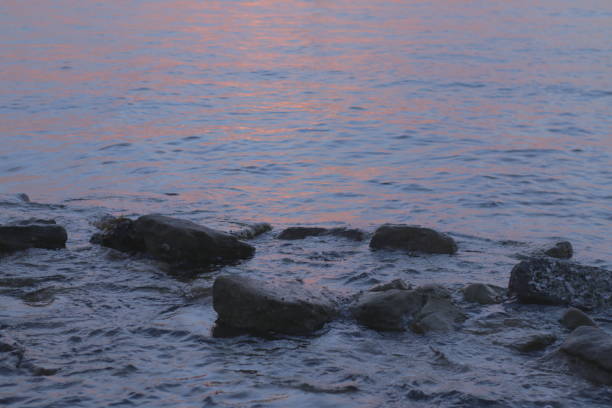 Cute girl in bikini sits at rock beach watching sunset in Sydney Harbour, Australia