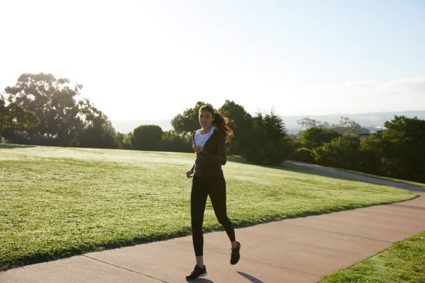 istock Fit young woman jogging on path in a park 1198382807