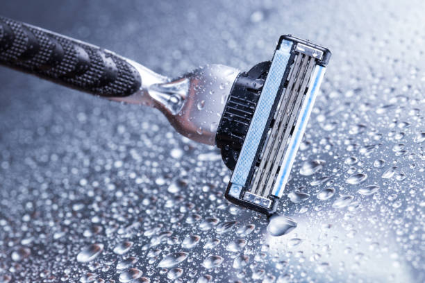 primer plano de la maquinilla de afeitar con gotas de agua sobre un fondo gris - wet shave fotografías e imágenes de stock