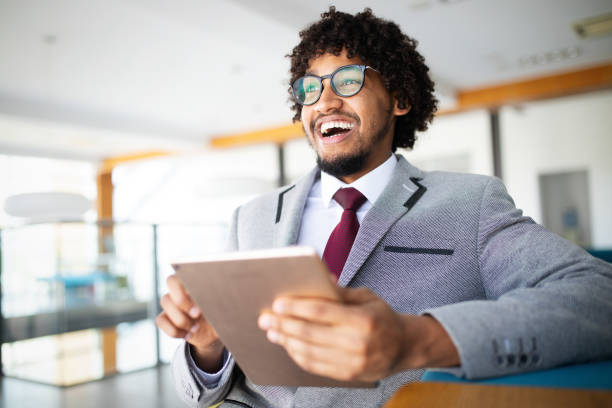 istock Handsome afro american businessman in classic suit is using a digital tablet 1198387426