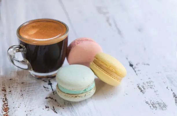 Macaron color pastel pink, yellow and mint top view copy space at right fogus on top of glass of coffee.