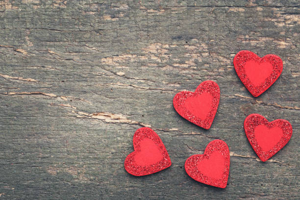 istock Red glitter hearts on gray wooden table 1198391284