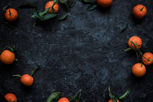 istock Fresh mandarin oranges with leaves on textured dark background 1198391512