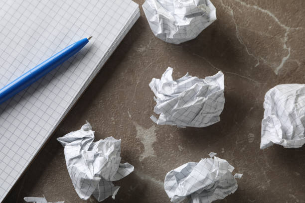 istock Paper balls, notebook and pen on grey table, close up 1198392118