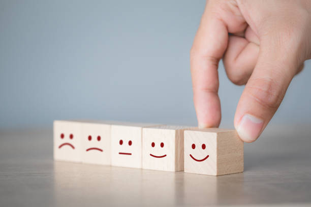 istock Customer pressing smiley face emoticon on wood cube, Service rating, satisfaction concept. 1198392454