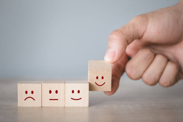 istock Customer pressing smiley face emoticon on wood cube, Service rating, satisfaction concept. 1198392479