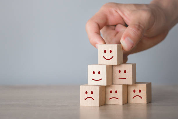 istock Customer pressing smiley face emoticon on wood cube, Service rating, satisfaction concept. 1198392577