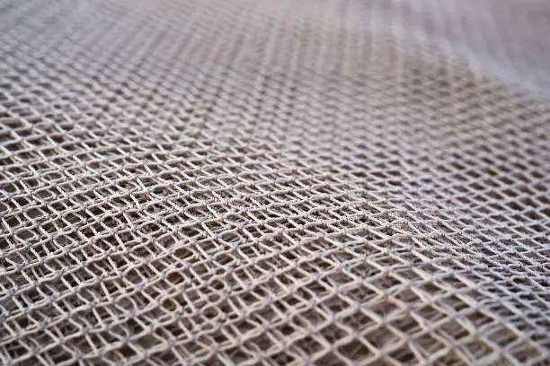 Photo of Close up view of fishing net in marine port in the morning. Selective focus. Blurred pattern background