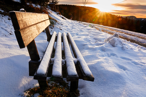 Snow covered bench at sunset