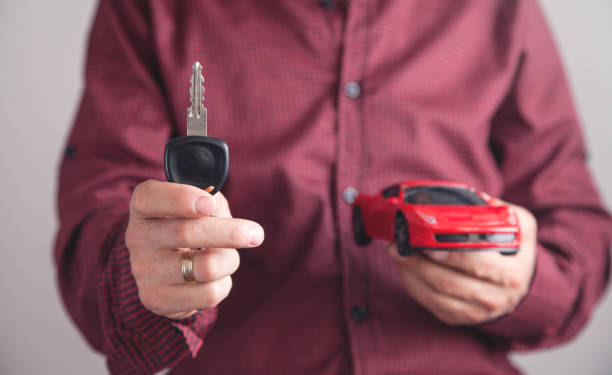 istock Man holding car key with car in office. 1198398704