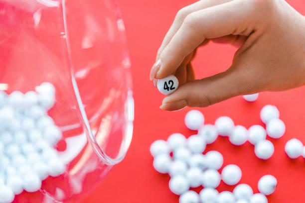 vue recadrée du nombre de fixation de femme près du bol en verre d'isolement sur le rouge - lottery balls photos et images de collection
