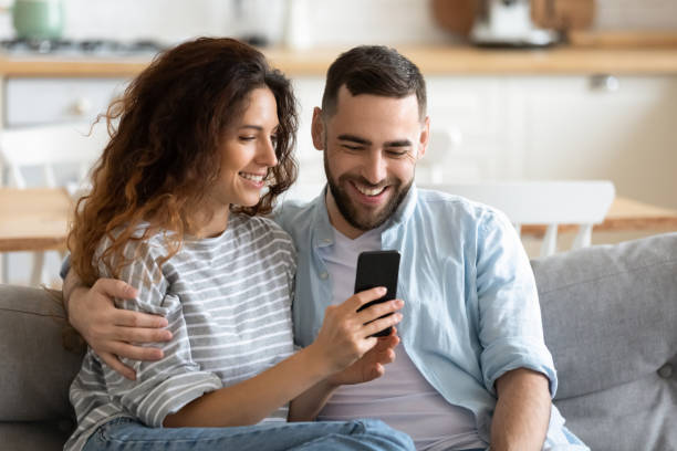 istock Couple in love resting on couch having fun using smartphone 1198401594