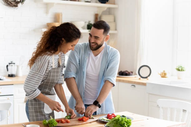 istock Couple preparing together vegetable salad standing in kitchen at home 1198401641