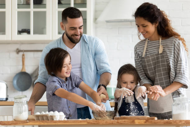 istock Married couple and kids preparing pie in kitchen at home 1198401659