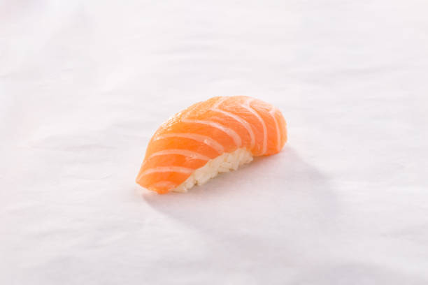 lachs niguiri sushi auf weißem zerknitterten papier hintergrund - sake nigiri stock-fotos und bilder