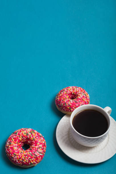 istock A cup of americano with two pink donuts on a blue background 1198405774