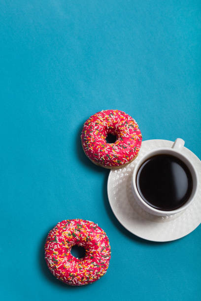 istock A cup of americano with two pink donuts on a blue background 1198405789
