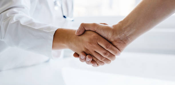 istock Female doctor shaking hands with man 1198407816