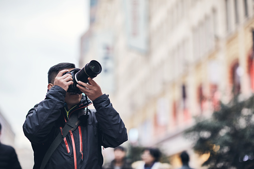 A male traveler in a city photographed with a digital camera。A male photographer takes photos on nanjing road in Shanghai, China.