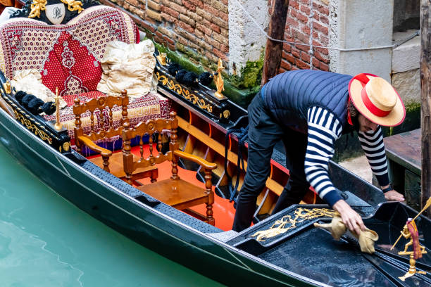 赤いバンド、ネイビーブルーのストライプシャツ、ベスト、パンツと麦わらボートの帽子を身に着けているイタリア語/ベネチアゴンドリエ。彼の派手なゴンドラボートで魅力的なオースマン - oarsman sport nautical vessel one person ストックフォトと画像
