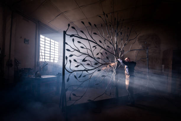 blacksmith artist working in his smithy studio creating a gate-tree - iron gate imagens e fotografias de stock