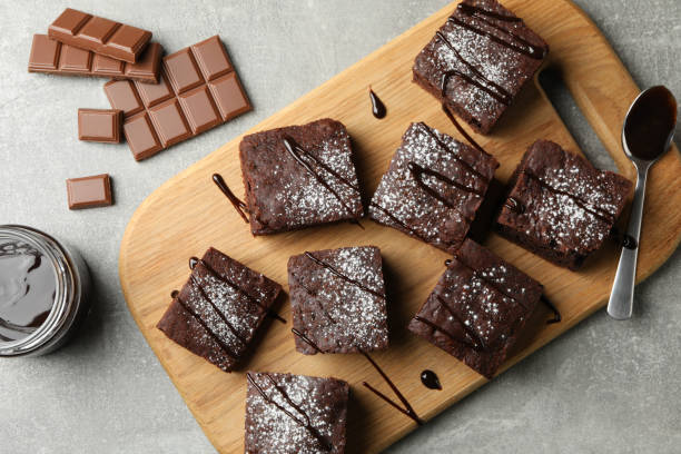 istock Board with chocolate cake slices and chocolate on grey background, top view 1198413190