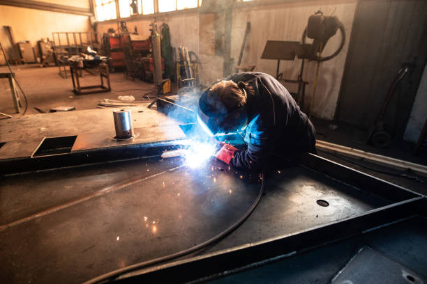 istock Experienced welder working on metal construction and welding iron parts in workshop. Weld sparks flying. 1198413280