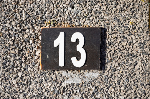 Number 13, thirteen, street number sign on the wall